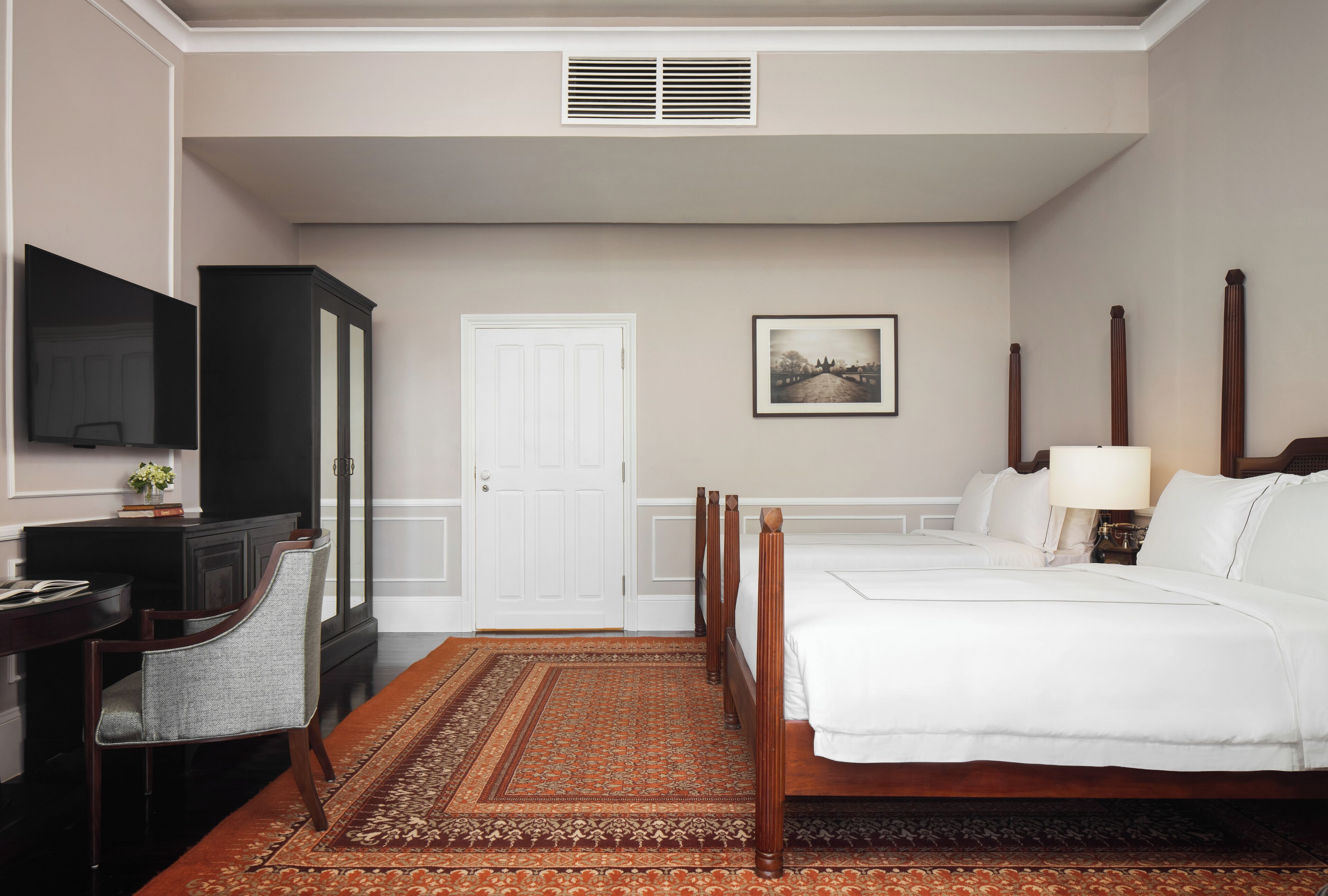 Une chambre d’hôtel comprenant un lit, un bureau avec une chaise, une télévision, une armoire et une porte.