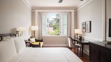 A hotel room with a large bed, a desk, a chair, a television, and a window with curtains.