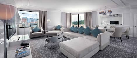 A modern hotel room with a large sofa set, a dining table, and a city view.