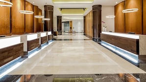 A modern hotel lobby with a long reception desk, wooden paneling, and a marble floor. - Paradox Singapore (Singapore)