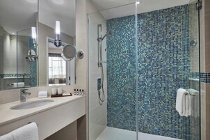 A modern bathroom with a glass-enclosed shower, a large mirror, and a tiled backsplash.