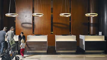 A reception area with a modern design, featuring a reception desk, a wooden wall with a decorative panel, and three pendant lights.