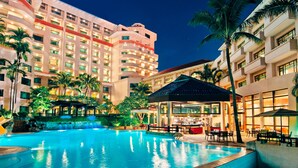 A hotel with a large outdoor pool, multiple balconies, and a well-lit bar area. - Paradox Singapore (Singapore)