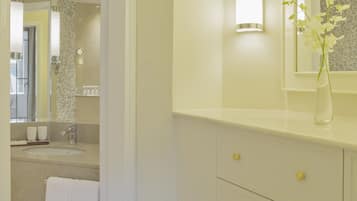 Een moderne badkamer met een witte wastafel, een spiegel en een vaas met bloemen.
