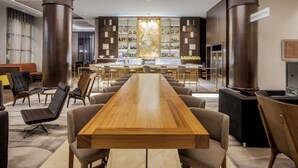 A modern bar area with a long wooden table, bar stools, and a well-stocked liquor cabinet. - Paradox Singapore (Singapore)