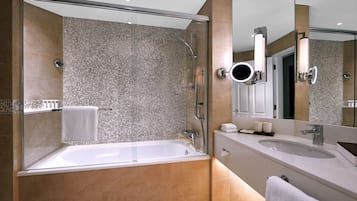 A modern bathroom with a glass-enclosed shower, a large bathtub, and a vanity with a sink and mirror.