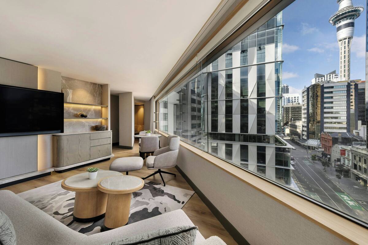A modern living room with a large window, a flat-screen TV, and a city view.