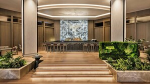 Un espace bar moderne doté d’un îlot central, de revêtements de sol en bois et d’un aménagement pour s’asseoir.