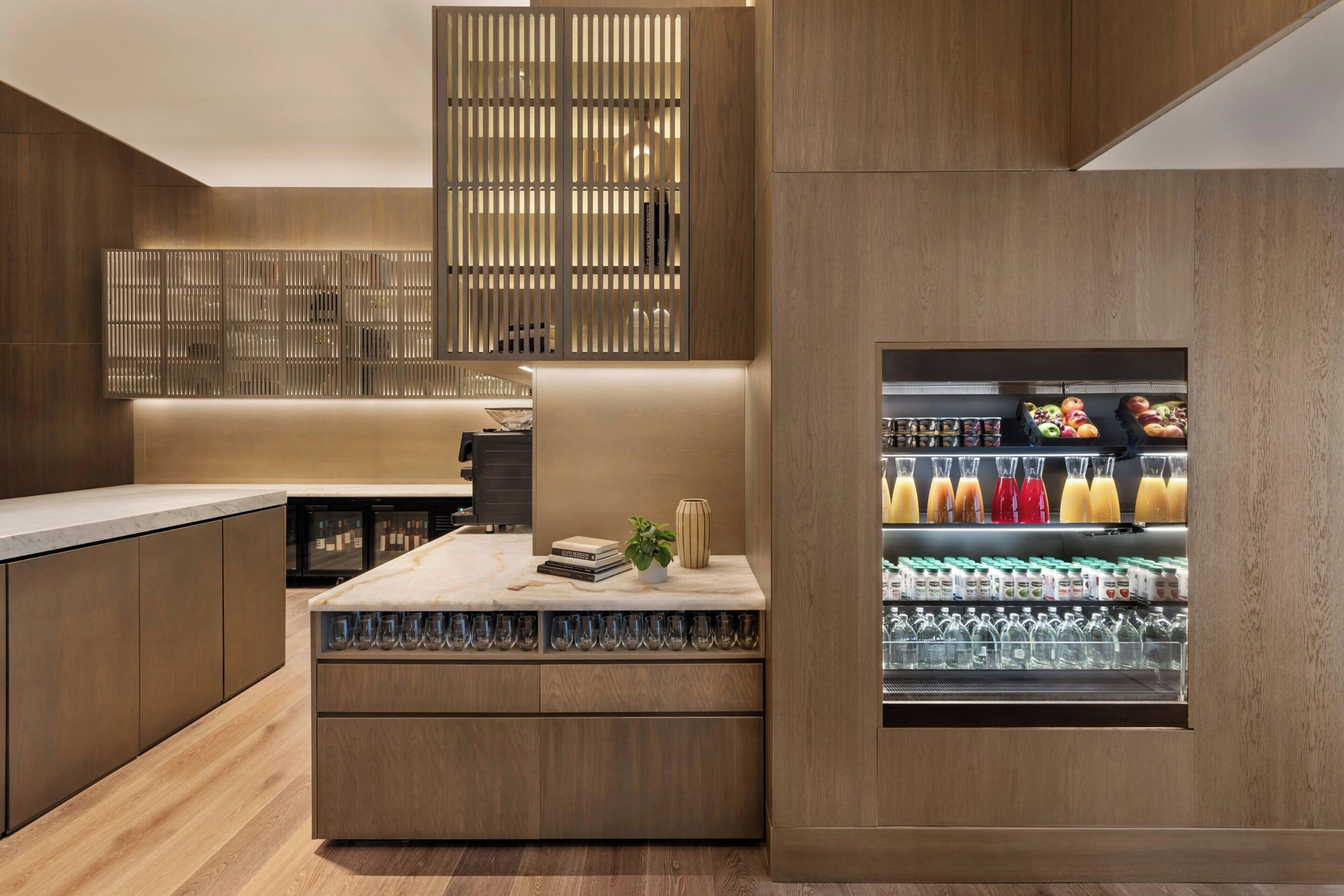 A modern kitchen with wooden cabinetry, a built-in bar area, and a beverage refrigerator.