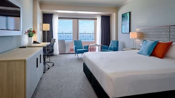 Habitación de hotel con cama, escritorio, sillas y un balcón con vistas.