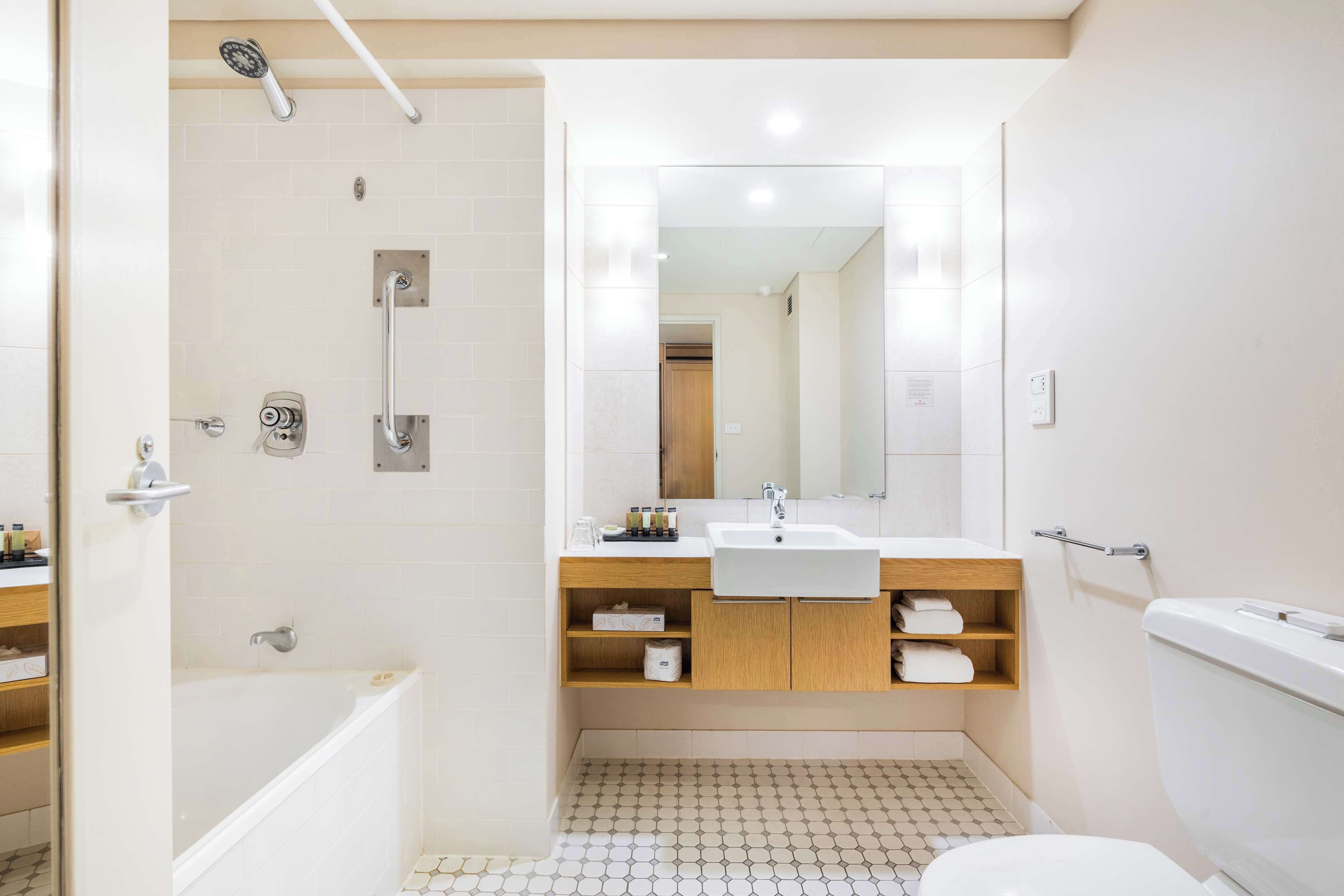 A modern bathroom with a bathtub, shower, sink, and toilet.
