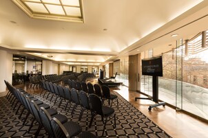A conference room with rows of chairs, a stage, a podium, and a large screen.