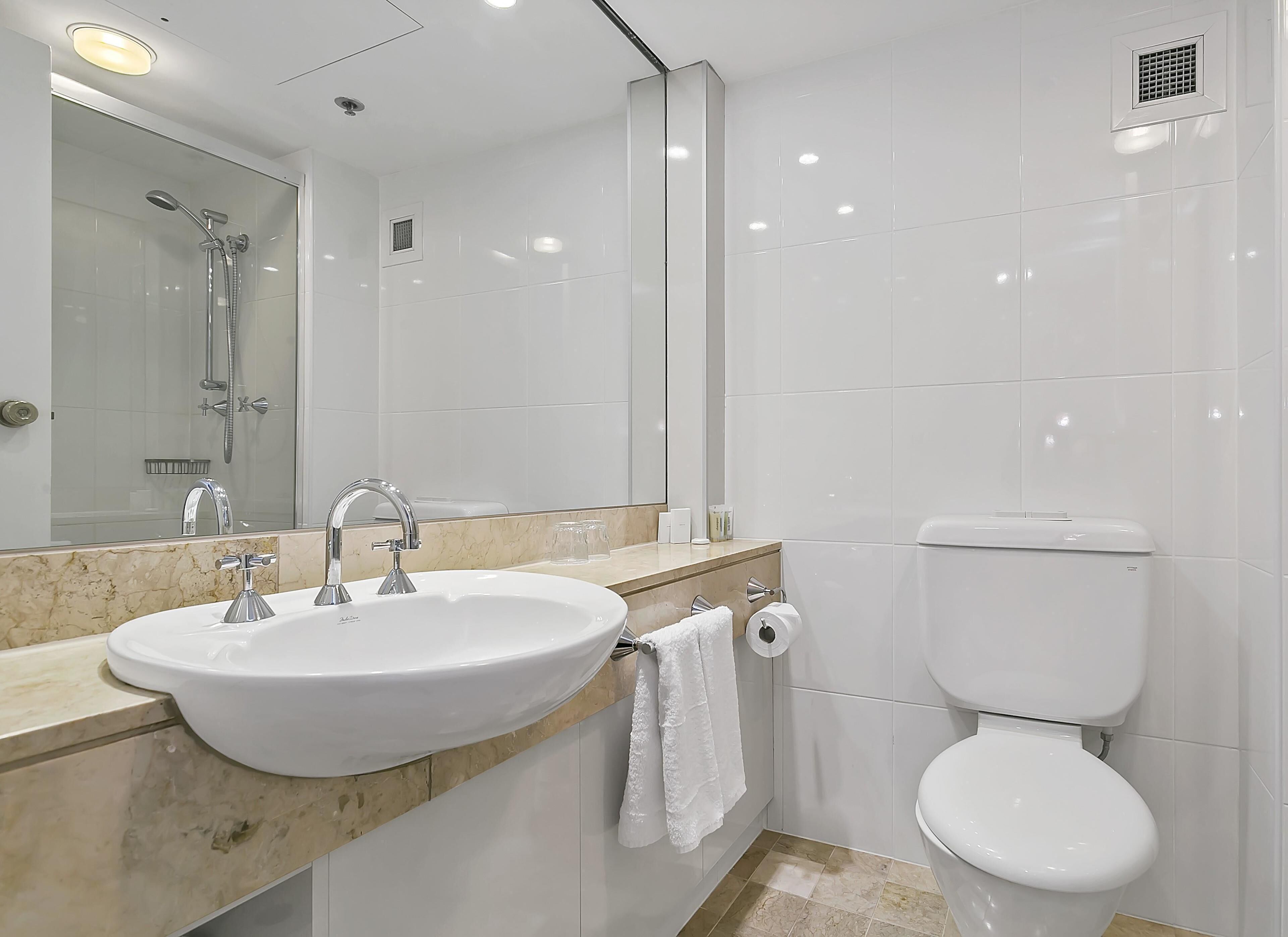 A modern bathroom with a sink, mirror, toilet, and shower.