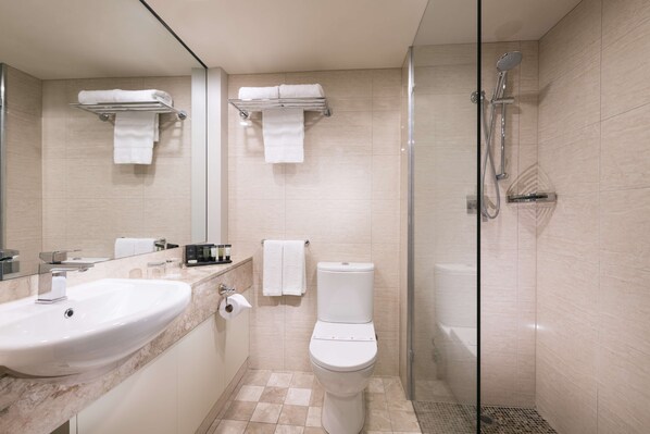 A modern bathroom with a large sink, toilet, and glass-enclosed shower. - Stamford Plaza Adelaide (Adelaide)