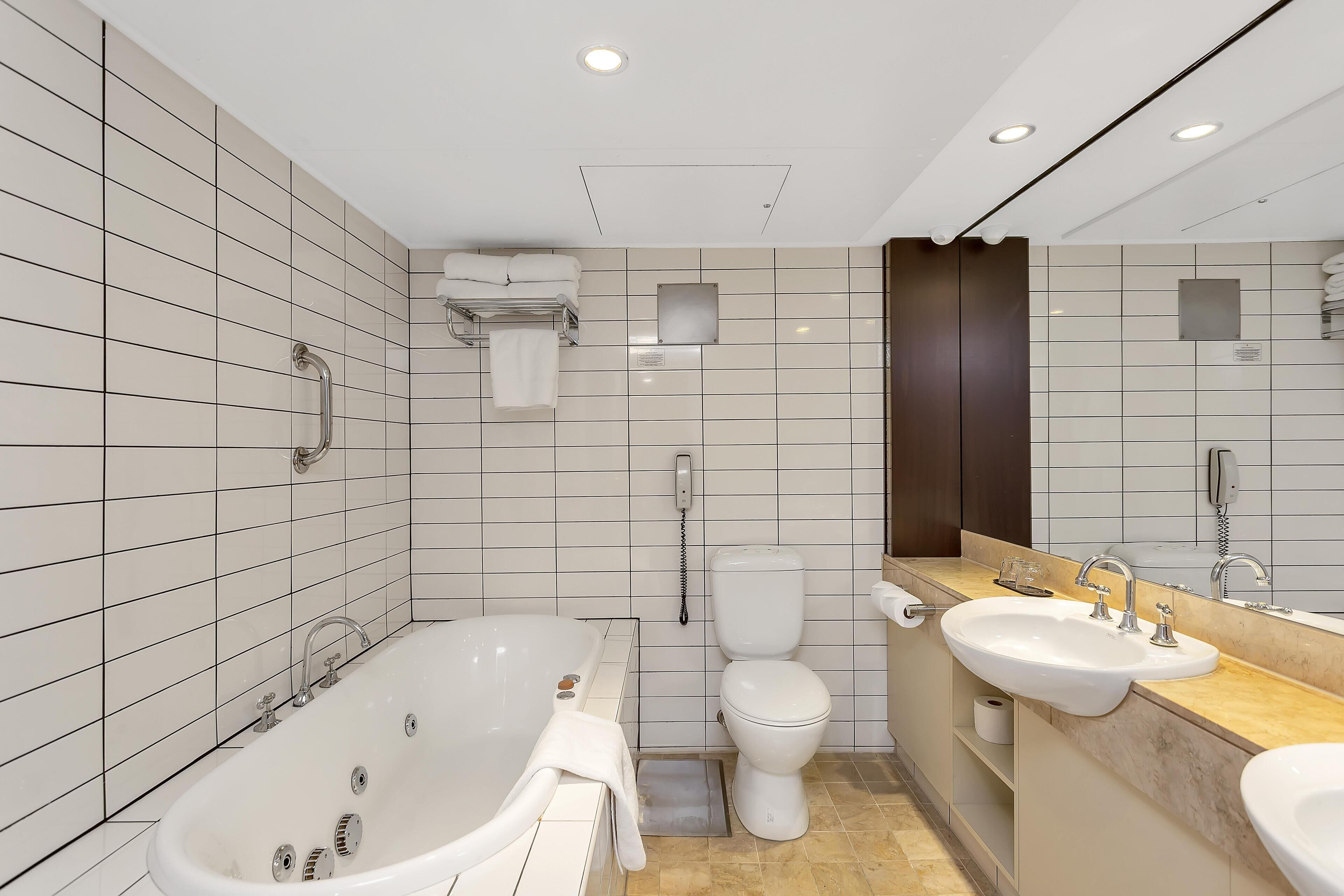 A modern bathroom with a bathtub, toilet, and two sinks.