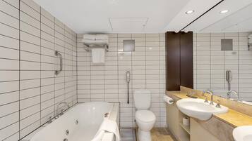A modern bathroom with a bathtub, toilet, and two sinks.