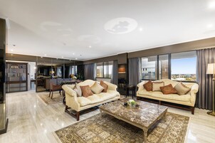 A spacious living area with two sofas, a coffee table, and a view of the city.