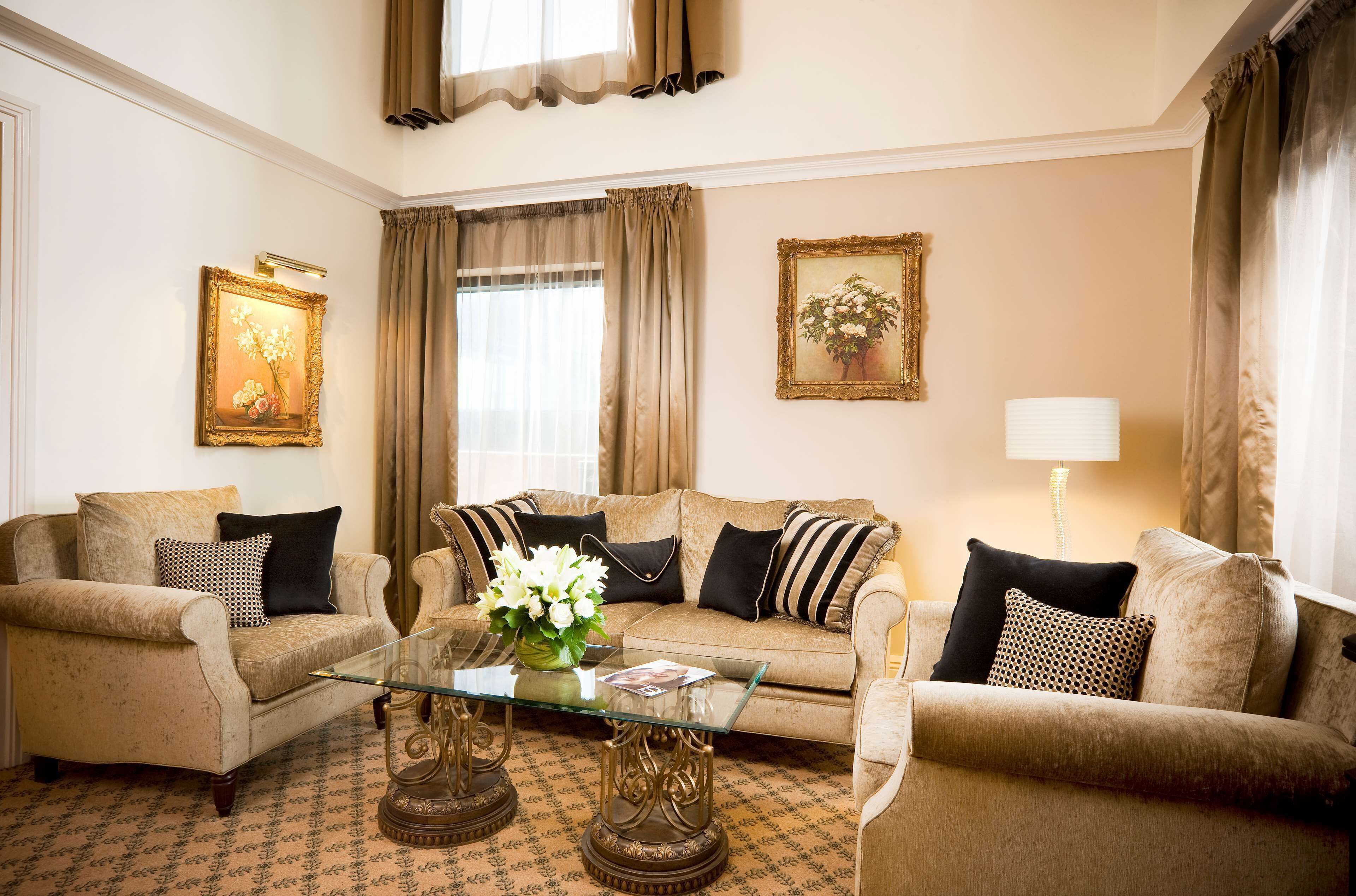 A living room with a sofa set, a glass coffee table, and two wall-mounted lamps.