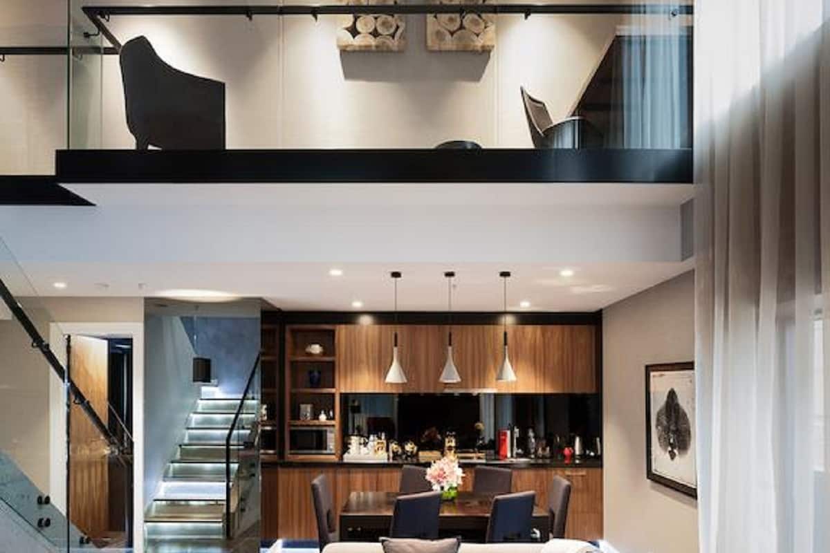 Un intérieur moderne avec un canapé, un coin repas et un escalier.