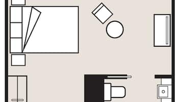 A hotel room layout with a bed, desk, chair, and a small bathroom area.