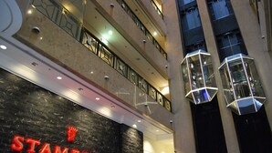 Un edificio de varios pisos con un llamativo letrero 'STAMFORD', balcones e iluminación geométrica moderna.