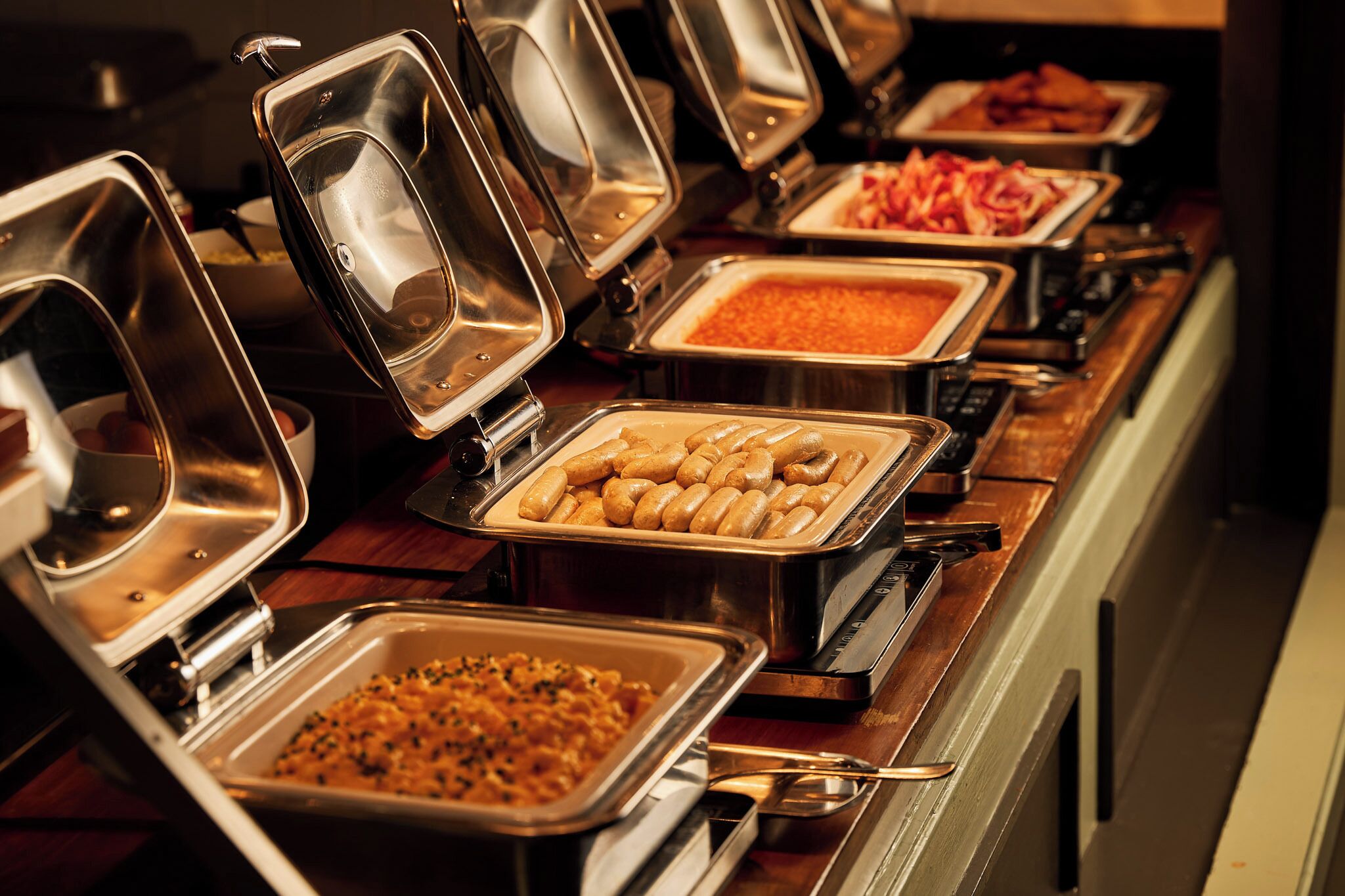 Un bufé con diversos alimentos en recipientes abiertos.