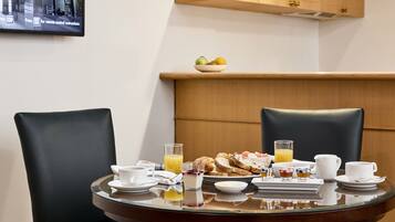 A breakfast setting with a table, chairs, and a fruit bowl on a shelf above.