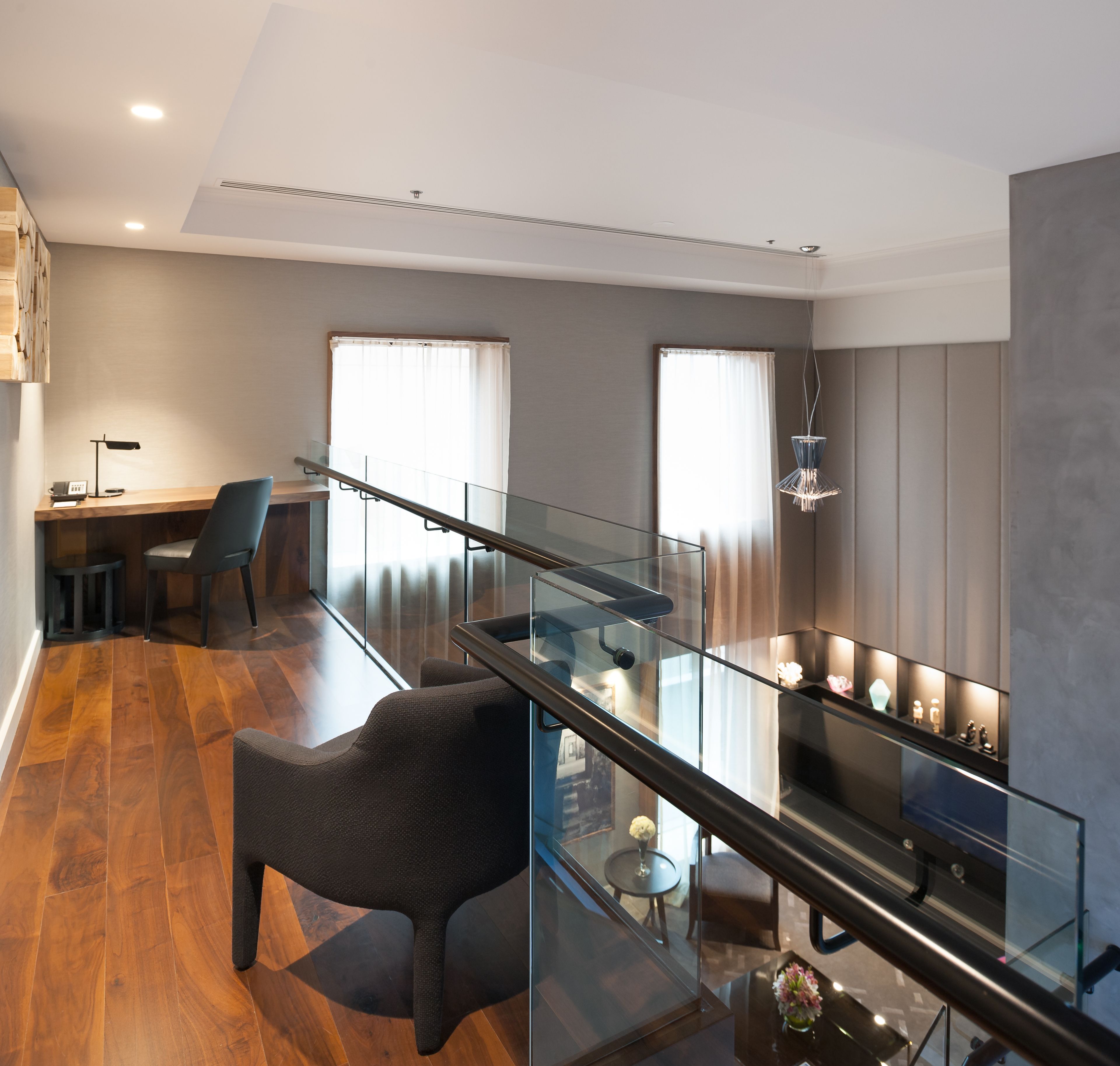 Un interior moderno con barandilla de vidrio, zona de comedor y escalera.