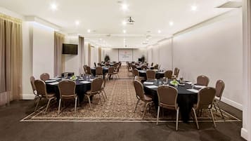 A conference room with multiple tables and chairs, a flat-screen TV, and a carpeted floor.