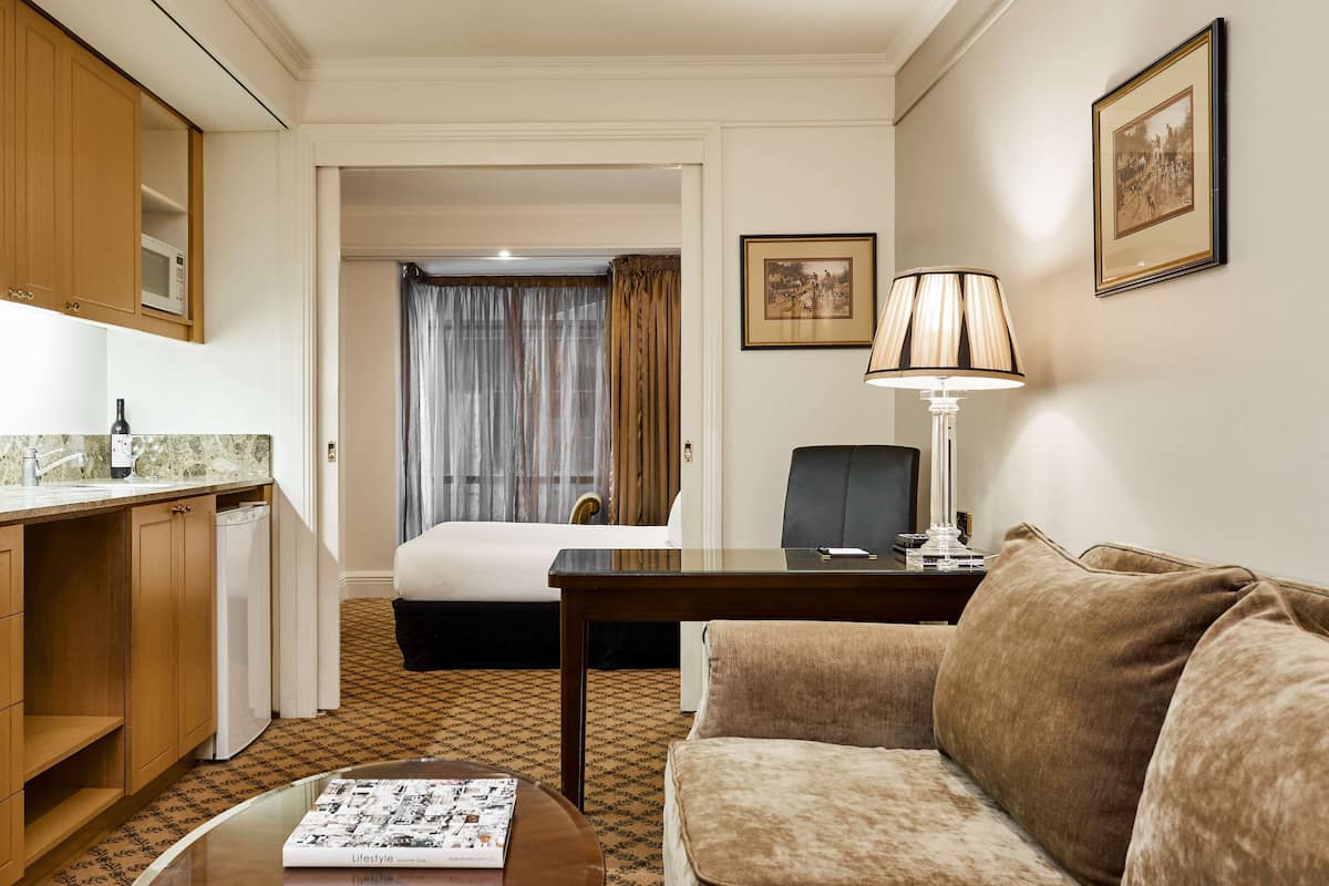 Une chambre d’hôtel comprenant un lit, un bureau, une lampe, un canapé, un coin repas avec un four à micro-ondes et un réfrigérateur.