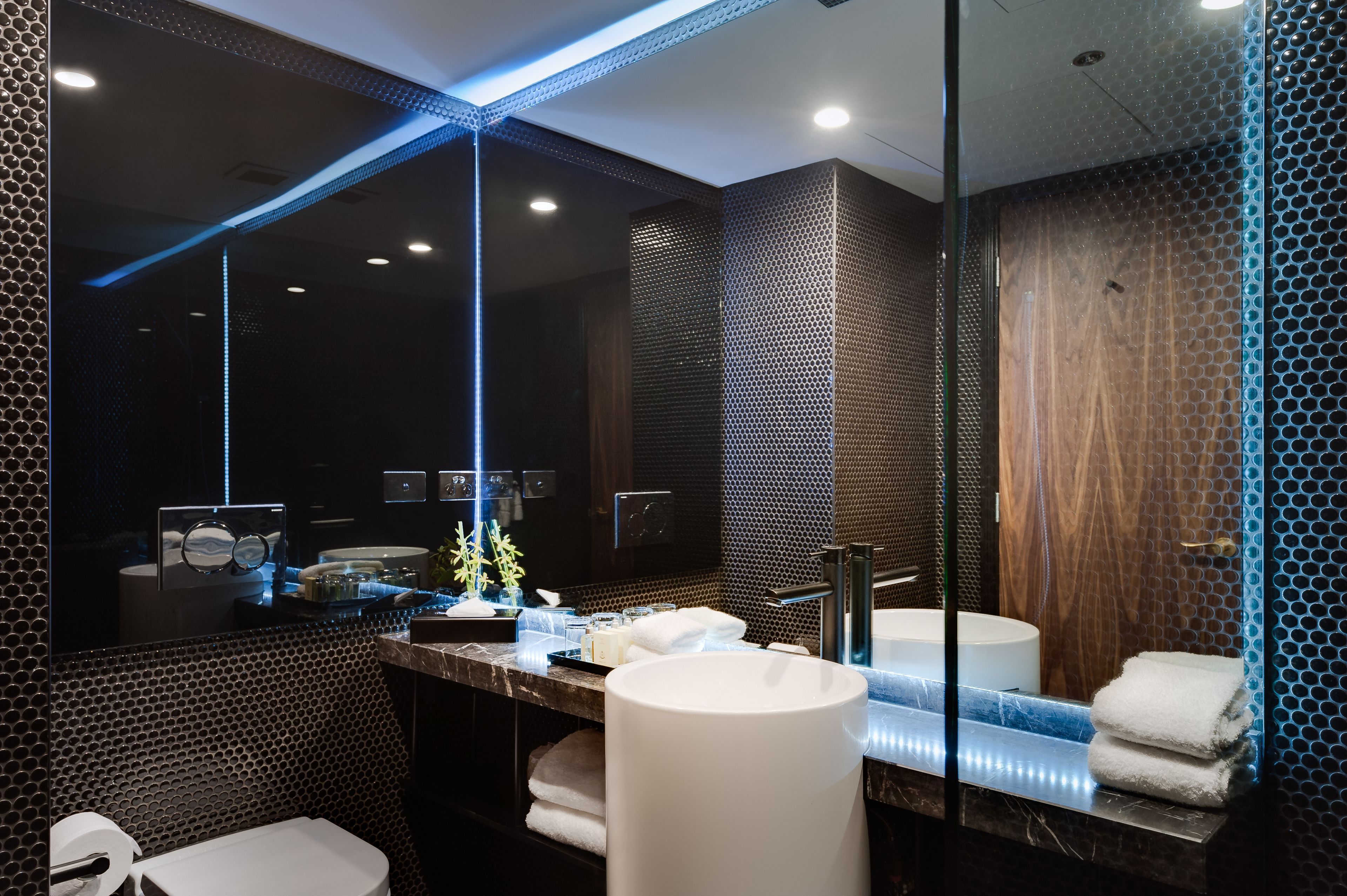 A modern bathroom with a large mirror, a sink, and a toilet.