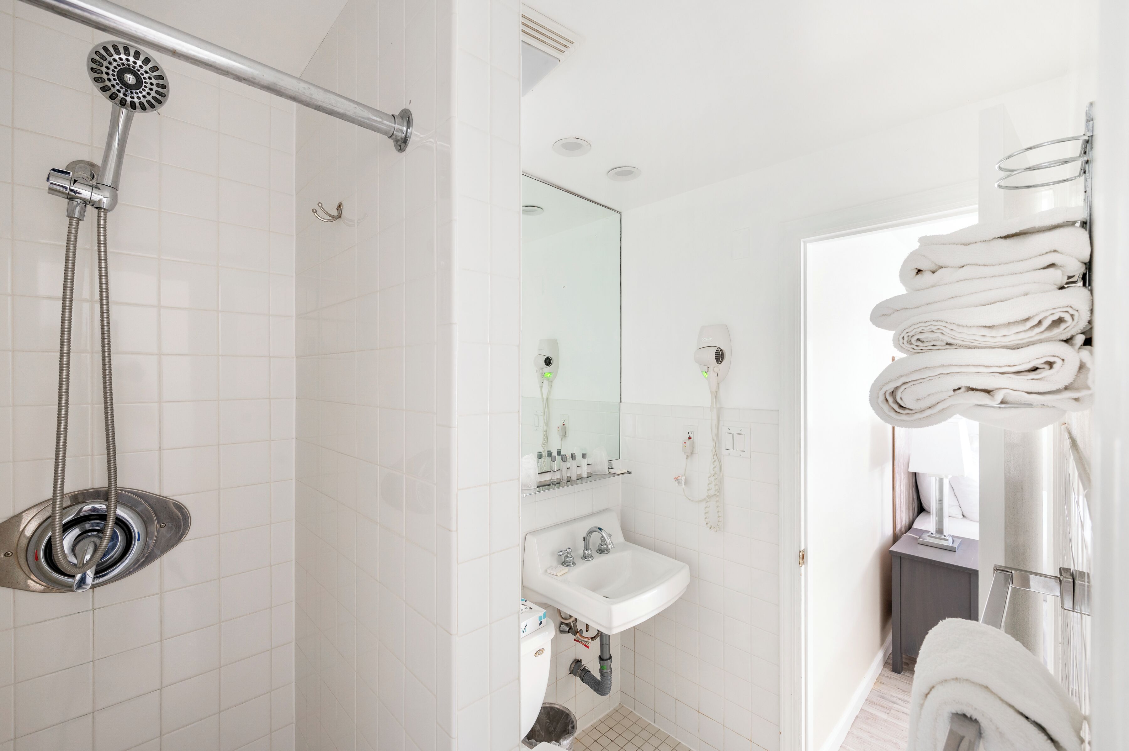 Un baño con ducha, lavamanos y toallero.