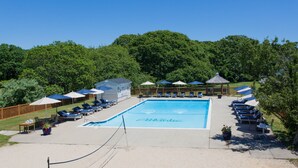 A swimming pool with lounge chairs and umbrellas, surrounded by a wooden fence and trees. - The Atlantic Hotel (Southampton)