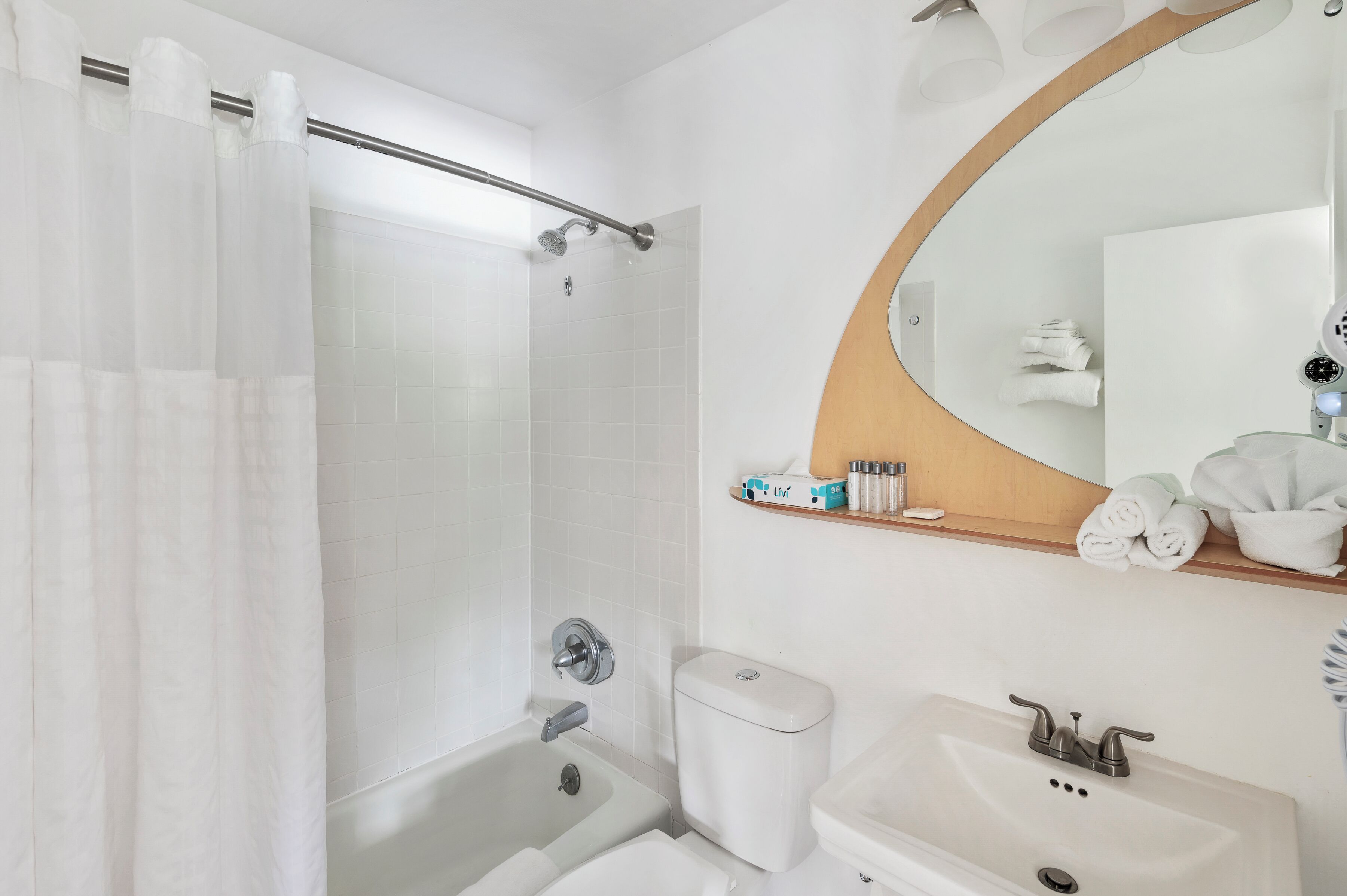 Un bagno con doccia, WC, lavandino e uno specchio con cornice in legno.