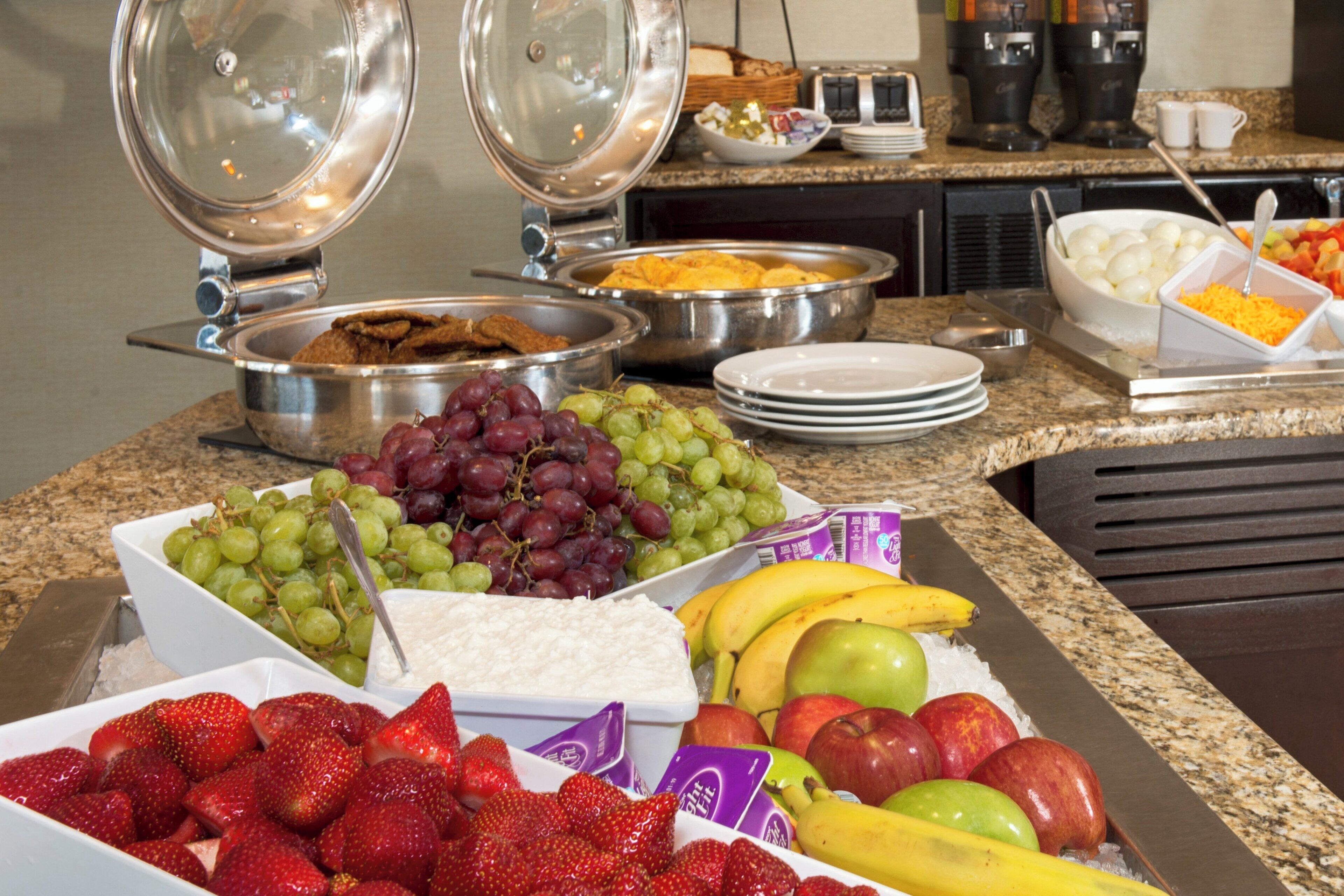 A buffet with various food items including fruits, cheeses, and bread.