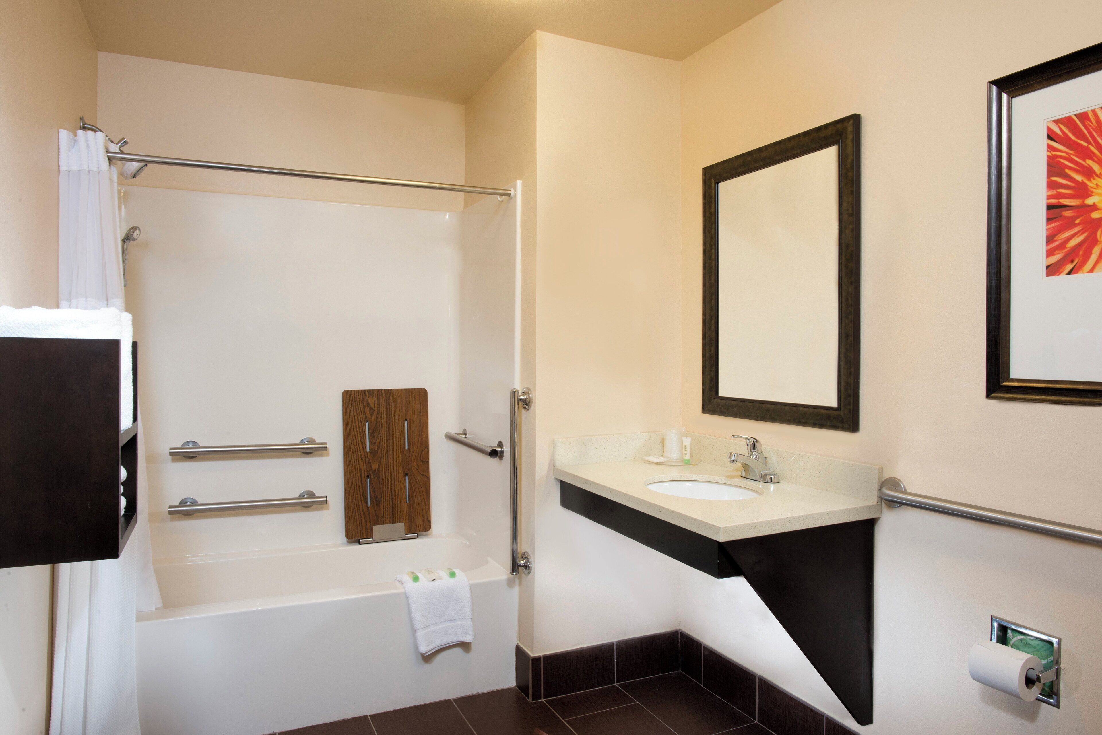 A modern bathroom with a bathtub, a vanity with a sink, a mirror, and a toilet paper holder.