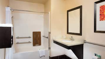A modern bathroom with a bathtub, a vanity with a sink, a mirror, and a toilet paper holder.