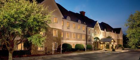 A multi-story hotel with a parking lot in front.