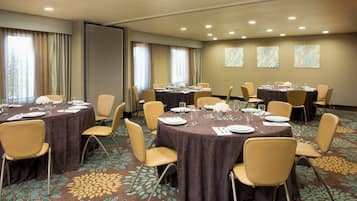 A conference room with round tables, chairs, and floral carpet design.