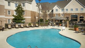 A swimming pool with lounge chairs and a covered seating area, surrounded by apartment buildings. - Staybridge Suites Myrtle Beach - West by IHG (Myrtle Beach)