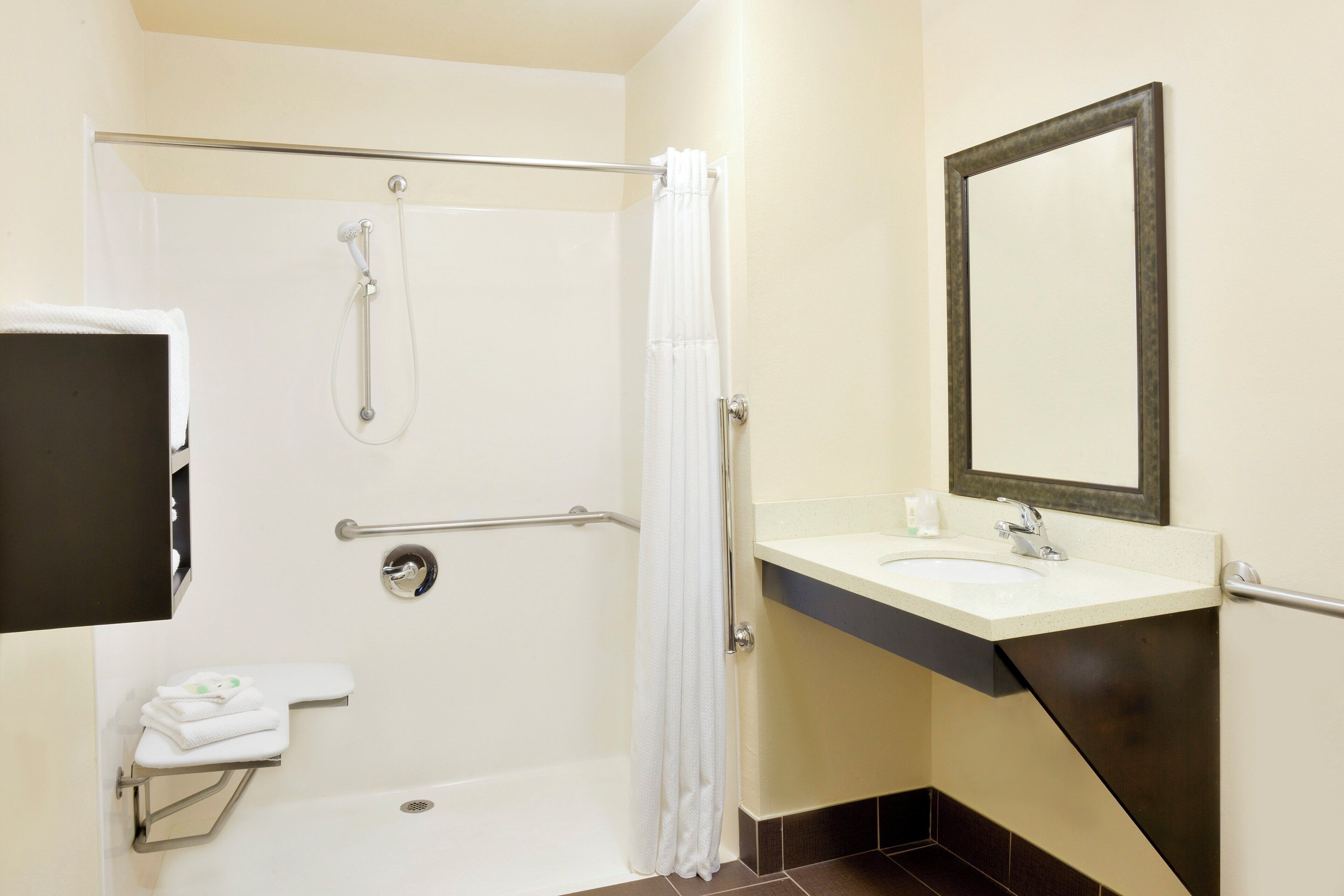 Une salle de bain équipée d’une douche, d’un lavabo, d’un miroir et d’un porte-serviettes.