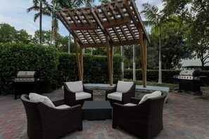 An outdoor patio with wicker furniture, a pergola, and two barbecue grills. - Staybridge Suites Miami Doral Area by IHG (Miami)