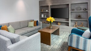A modern living room with a grey sofa, a blue armchair, and a coffee table. - Staybridge Suites Miami Doral Area by IHG (Miami)