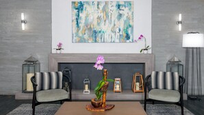 A modern living room with a fireplace, two armchairs, a coffee table, and decorative items including orchids and lanterns. - Staybridge Suites Miami Doral Area by IHG (Miami)