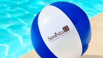A blue and white beach ball with the text "Sonesta Suites" by the edge of a swimming pool.