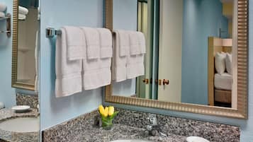 A bathroom with a granite countertop, a white sink, a mirror, and a towel rack with two towels.