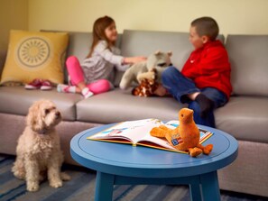 A living room with a round blue table, a sofa, and two children playing with toys. - Staybridge Suites Irving Las Colinas by IHG (Irving)