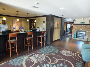 A hotel lobby with a bar area, seating, a fireplace, and a reception desk. - Staybridge Suites Irving Las Colinas by IHG (Irving)