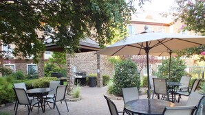 An outdoor patio with brick flooring, outdoor furniture, and a grill.