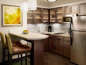 Cozinha moderna com ilha central, eletrodomésticos de aço inoxidável e painel de azulejos.